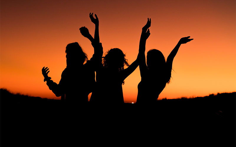 Picture of girls dancing with the sunset as a backdrop