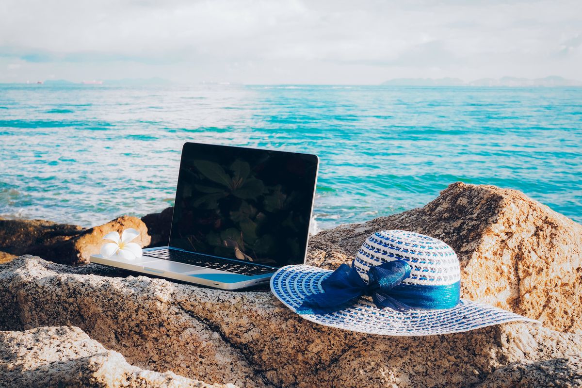 Laptop and sunhat by the sea