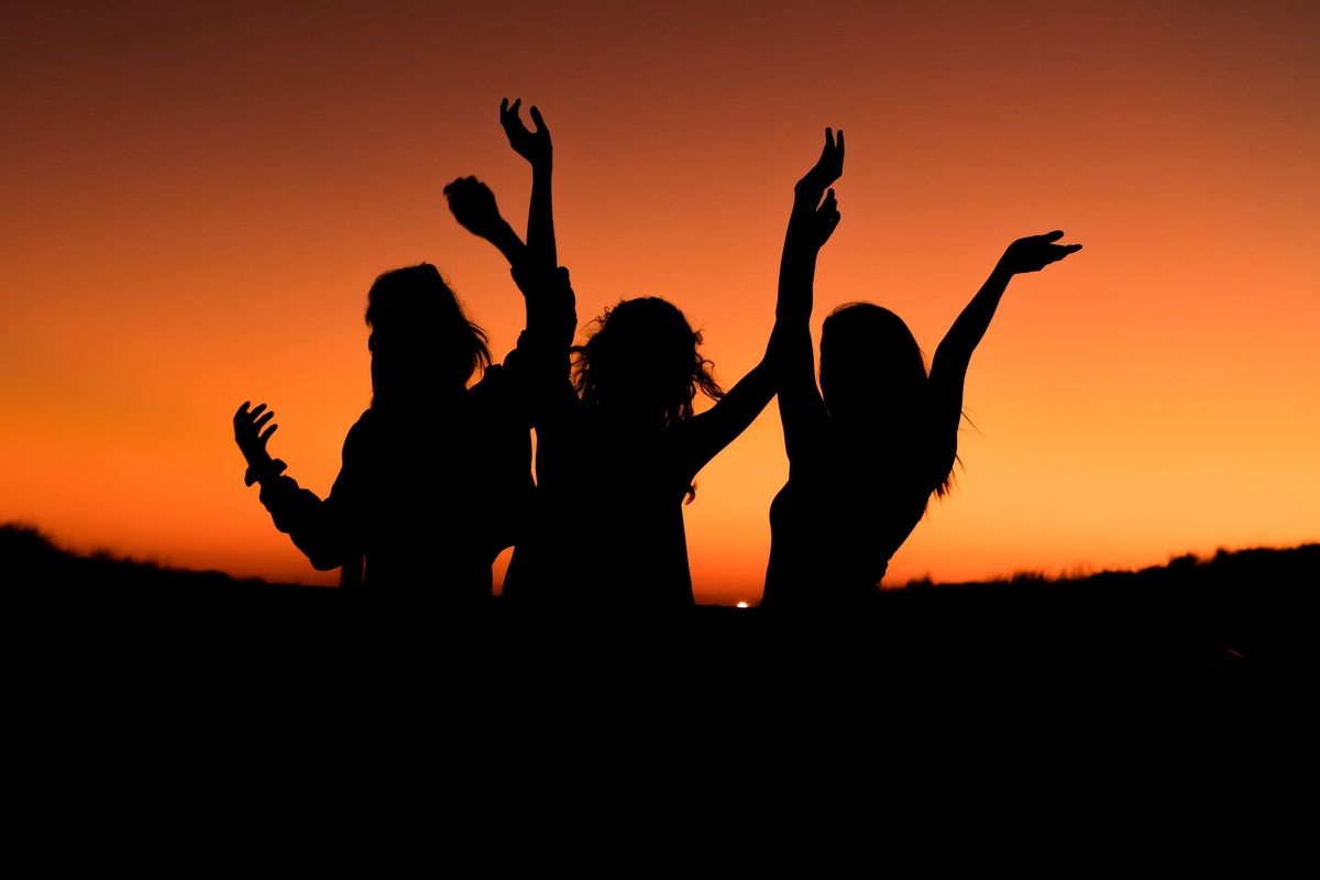 Silhouette of three girls dancing at sunset.